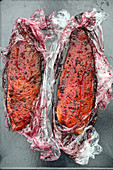 Salmon trout fillets being marinated in clingfilm