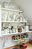 Old jugs and storage jars on kitchen shelves under sloping ceiling