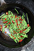 Grüne Bohnen und getrocknete Tomaten auf dem Grill garen