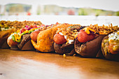 Row of assorted hot dogs with different delicious toppings and fillings