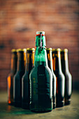 Eine grüne Bierflasche vor vielen braunen Bierflaschen