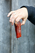 A hand holding a marinated tuna fillet