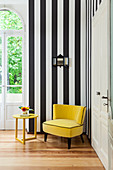 Yellow velvet armchair and side table against black-and-white striped wall
