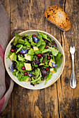 A mixed green salad with avocado, redcurrants and borage flowers
