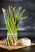 Bunch of asparagus tied with kitchen twine, on a piece of hemp sack