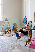 Soft toys seated at table and in tent in child's bedroom