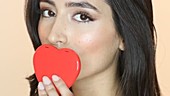 Woman kissing red heart shape