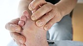 Man rubbing toes on bare foot