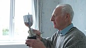 Elderly man inspecting trophy