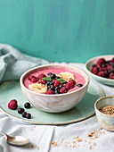Smoothie bowl with raspberries, blueberries, bananas, fresh mint and sesame seeds