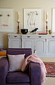 Purple armchair in front of antique sideboard in living room