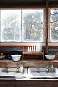 Zwei Waschbecken und Abtropfgestell mit Tellern vorm Fenster