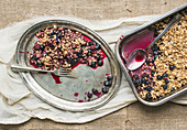Oat granola with fresh berries on a silver dish with a fork on a sackcloth background