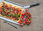 Rustikale Pizza mit Rohschinken, Salami, Tomaten und Rucola