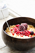 A smoothie bowl with granola, banana and frozen red fruits