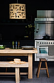 Rustic wooden table with stools and bench in black kitchen