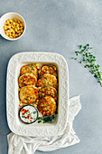 Corn fritters served with yogurt sauce and fresh thyme on the side in a white pan