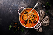 Seafood soup with prawns, mussels and tomato on dark background