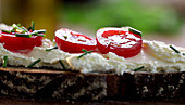 Bread topped with cream cheese, tomatoes and chives