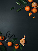 Mandarinen, ganz und geschält auf schwarzerm Untergrund (Aufsicht)
