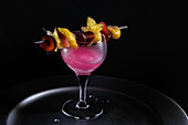 A pink drink with an exotic fruit skewer