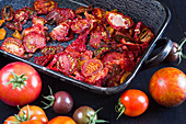 Dried tomatoes in an enamel dish next to fresh colourful tomatoes