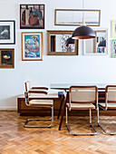 Cantilever chairs around dining table in front of pictures and mirrors on wall