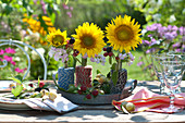 Lustige Tischdekoration mit Sonnenblumen in Garnrollen
