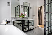 Mirrored washstand, wall- mounted mirrors, bathtub and shower cubicle in bathroom