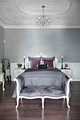 Double bed and bedroom bench in elegant bedroom with stucco ceiling