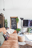 Braunes Ledersofa, im Hintergrund Kreidetafel, Stehleuchte und Vintage Fernsehtisch im Wohnzimmer