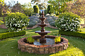 Dreistufiger, klassischer Brunnen in gepflegtem Landschaftsgarten