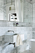 Marble sink in the bathroom with mirror cabinet and marble tiles