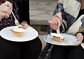 Two women sitting on stone steps eating slices of pumpkin pie
