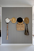 Summer hats and bags on coat rack on grey board wall