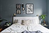 Double bed with white bed linen in bedroom with blue-grey wall