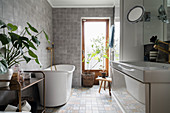 Free-standing bathtub in bathroom with grey floor tiles