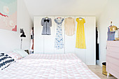 Bed and walk-in wardrobe with dresses hung on front in bedroom