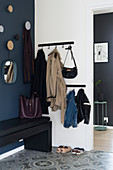 Coat rack and bench in foyer area with dark blue wall