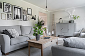 Grey sofas, wooden coffee table, houseplants and gallery of photos in living room