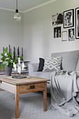 Grey sofas, wooden coffee table, houseplants and gallery of photos in living room