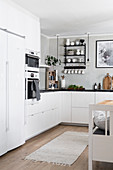 White kitchen counter with black worksurface with fitted appliances