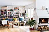 Shelving, plastic couch with colourful cushions and armchair in living room with open fireplace in foreground
