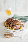 Marinated, oven-roasted pork knuckle with a herb and spice crust served with roast potatoes