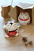 Asiatische Katzen aus Keramik auf bemaltem Papier