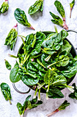 Young leaves of spinach in a metal bowl on a concrete background