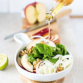 Veganer Salat mit Fenchel, Rucola und Apfel, mit Öl beträufeln