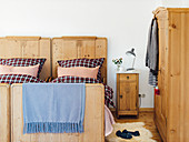 A rustic wooden bed with checked bedclothes, a bedside table and a wardrobe