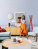 Woman leaning against sideboard in living room with designer furniture