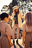 A young woman wearing a hat and children wearing uniforms at a photo shoot